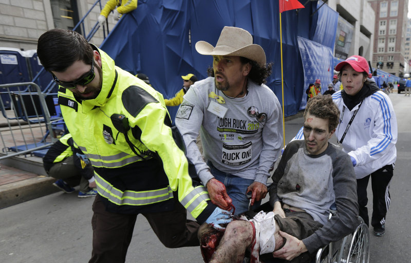 A medical responder and Carlos Arredondo, in cowboy hat, run an injured man past the finish line following an explosion at the Boston Marathon on Monday. Two explosions shattered the euphoria of the race, sending authorities out on the course to carry off the injured while stragglers were rerouted away from the smoking site of the blasts.