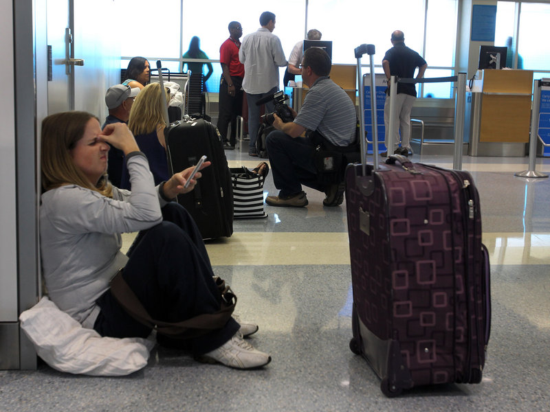 Stranded passenger Alexis Bennett waits for her flight to Chicago in Terminal A at Dallas-Fort Worth International Airport on Tuesday. American Airlines grounded flights across the country because of an outage in its main reservations system. Thousands of passengers were stranded across the country.