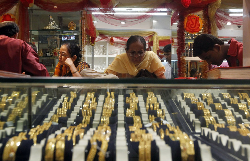 An Indian woman looks at a display of gold jewelry at a shop in Mumbai, India. The price of gold dropped 13 percent in two days recently.
