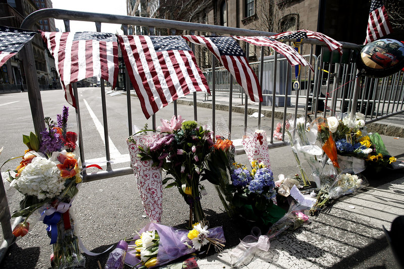 Flowers are placed by a Boston police barricade near the finish line of the Boston Marathon in Boston, Tuesday, April 16, 2013.