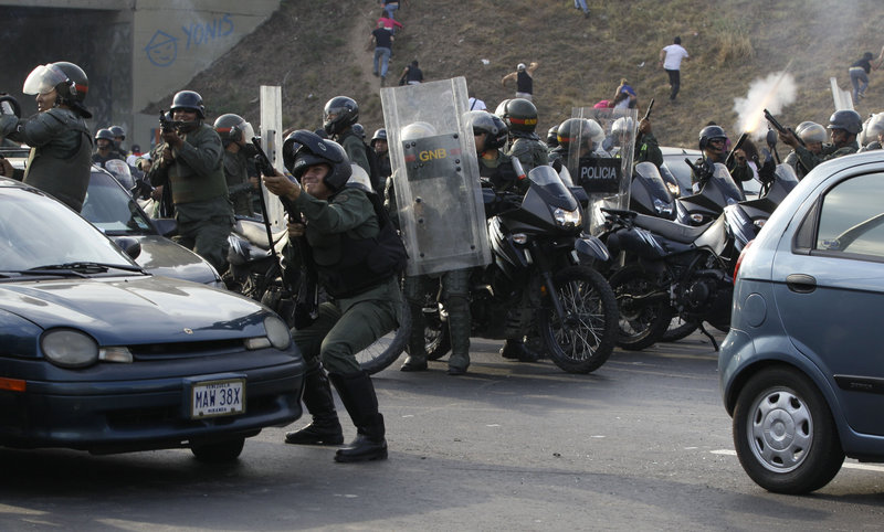 Riot police fire rubber bullets at demonstrators throwing rocks after opposition supporters blocked a highway Monday in Caracas, Venezuela, to protest election results.