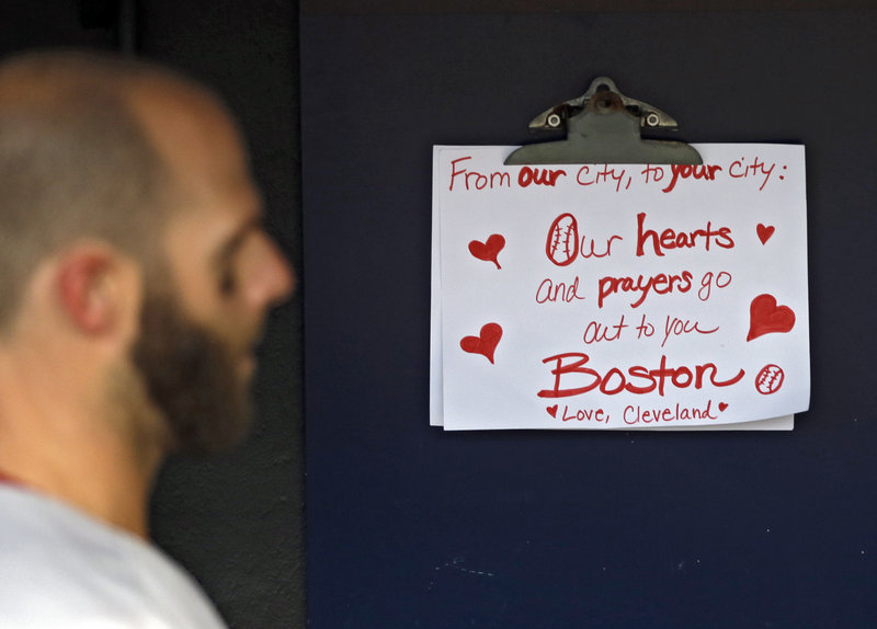 Dustin Pedroia of the Red Sox walks past a condolence sign in the dugout. The sign was written by a young Cleveland fan.