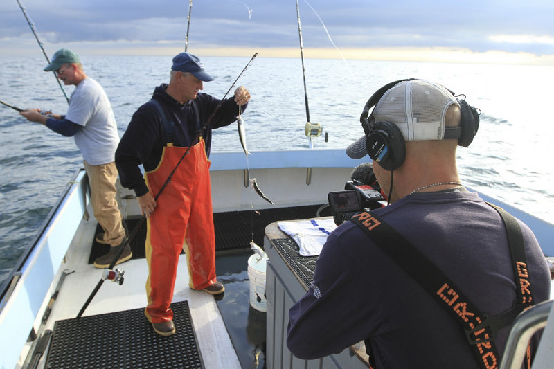 Cameraman River Hagg films first mate Bruce Hebert of North Waterboro, second from left, as he rigs bait fish with deckhand Kevin Twombly, left, aboard the fishing boat Lisa & Jake in Gloucester, Mass., on the current season of “Wicked Tuna,” airing on the National Geographic Channel.