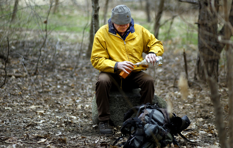 David Belibeau pours himself a beer in the woods of West Commercial Street, where homeless camps are being cleared after a man perished in a tent fire earlier this month.