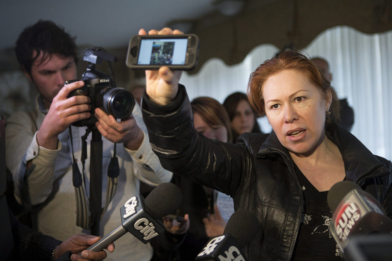 Maret Tsarnaev, an aunt of the two suspects in the Boston Marathon bombing, holds a reporter’s smartphone, which displays a scene from the bomb site, as she speaks to journalists Friday at her apartment building in Toronto.