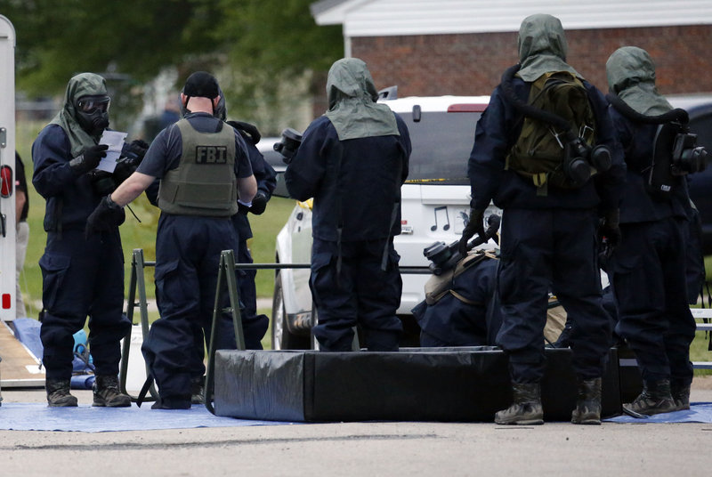 Federal agents wearing hazardous material suits and breathing apparatus begin cleaning up after searching the home of Paul Kevin Curtis in Corinth, Miss., Thursday evening.