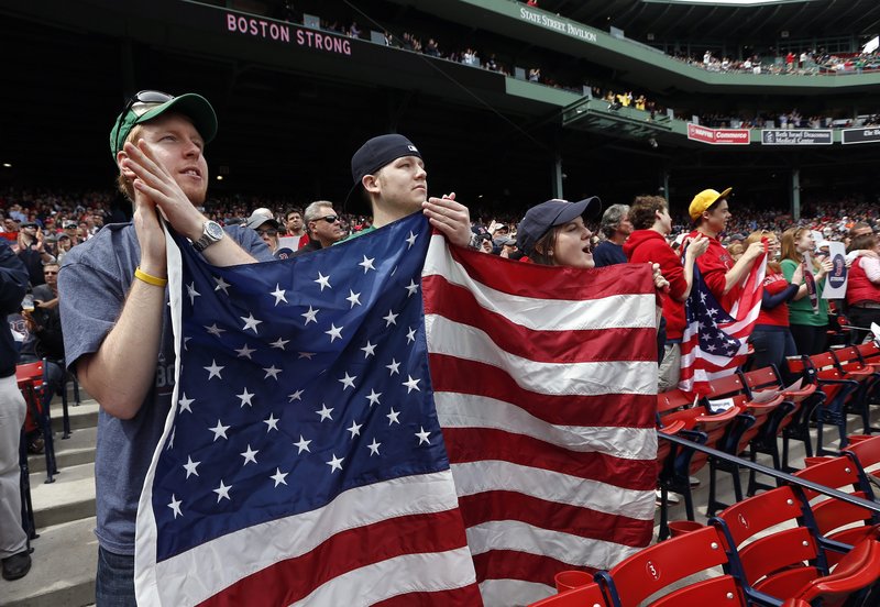 Red Sox fans display an American flag during pregame ceremonies at Fenway Park on Saturday. It was the team’s first home game since the Boston Marathon bombings. The Sox planned to autograph their uniforms and auction them off to raise money for a charity to benefit victims of last week’s violence.