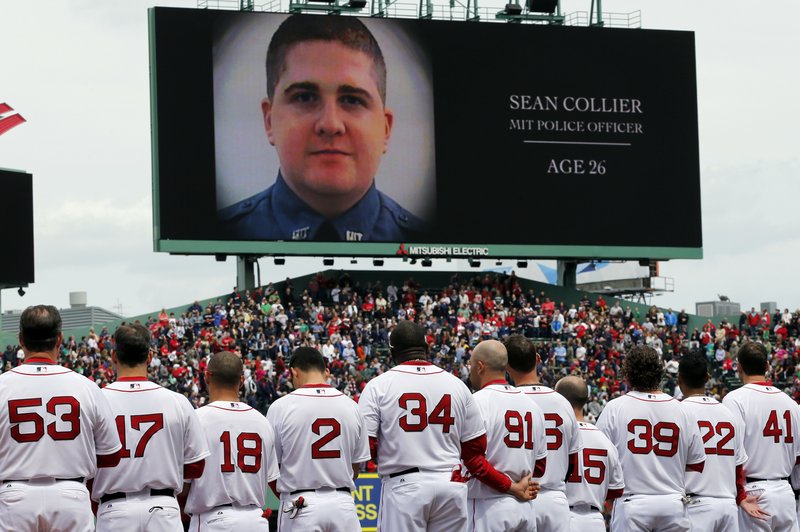 The Boston Red Sox line up during an emotional tribute to victims and survivors of the Boston Marathon bombings, as an image of slain Massachusetts Institute of Technology Police Officer Sean Collier is displayed on the scoreboard. Collier was killed in a confrontation with the bombing suspects Thursday night.