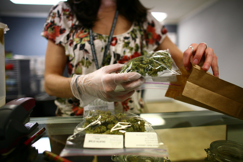 Sales associate Crystal Guess packages up a patient’s order inside the Good Meds medical cannabis center in Lakewood, Colo. Washington and Colorado are the only two states that have fully legalized the drug.