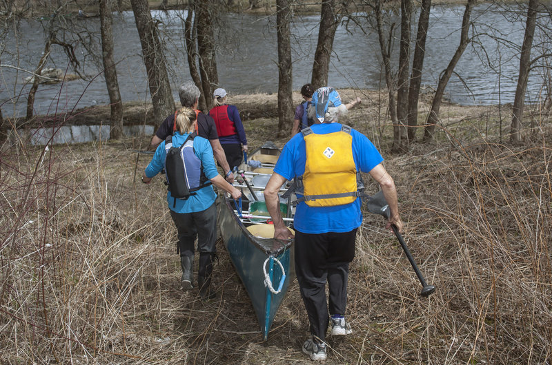 A voyageur canoe needs all of its crew to help with a portage – a group effort seen here at 6 Mile Falls on the Kenduskeag.