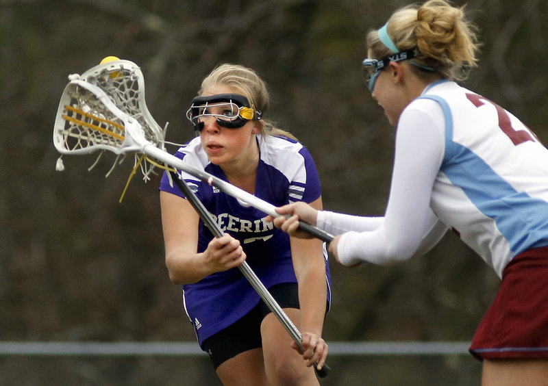 Maddy Mazjanis of Deering keeps her eyes on the ball while trying to keep it away from Lauren Coughlin of Windham. The game was the first of the season for both teams.
