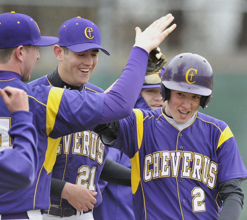 Charlie Mull of Cheverus, right, is welcomed by teammates Tuesday after scoring on a Sanford throwing error. The Stags came away with a five-inning victory against the Spartans, 10-0.