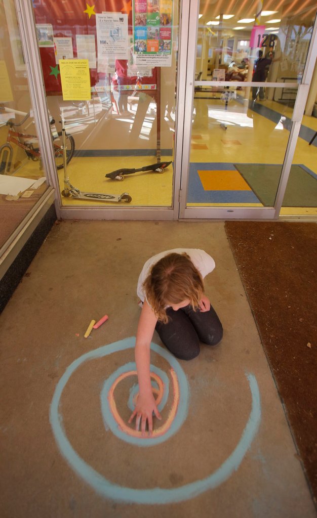 Hanna Harrington, 10, draws a chalk design in the entryway of the Joyful Harvest Neighborhood Center on Thursday.