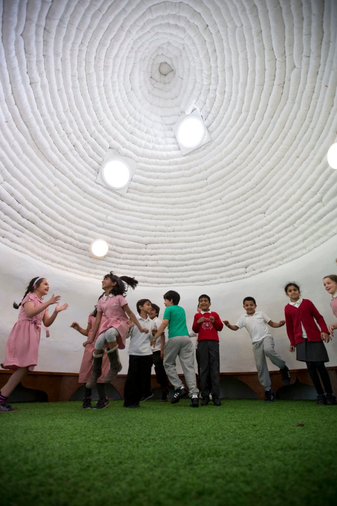 School pupils ages 6 and 7 play inside “The Big Adobe,” built on their playground in London on Thursday.