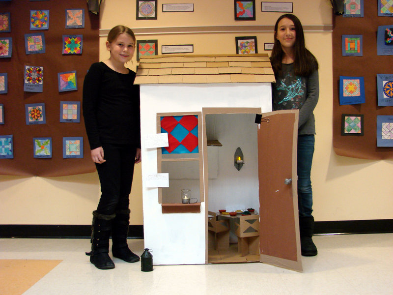 Wells Elementary School students Amanda Ring and Isabella DeAngelis stand by a miniature cardboard replica of a safe house they created as part of a display for a class study on the “Underground Railroad” recently.