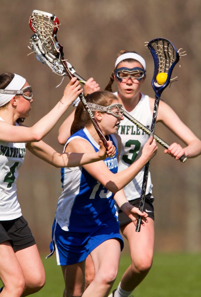 Hayley Fecko of Kennebunk attempts to manuever the ball between defenders Sofia Canning, left, and Heidi Cole of Waynflete during their girls’ lacrosse game Saturday. Waynflete pulled away to a 16-1 victory.