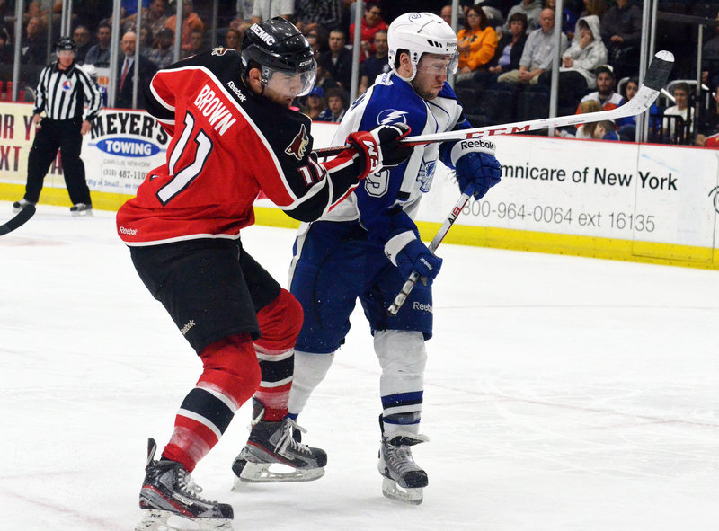 Portland’s Chris Brown takes a shot as he jousts with Syracuse’s Tyler Johnson during first-period action of Game 2 of the first round of the Calder Cup series in Syracuse, N.Y., won by the Crunch. Down 2-0, the Pirates must win Thursday to avoid elimination.