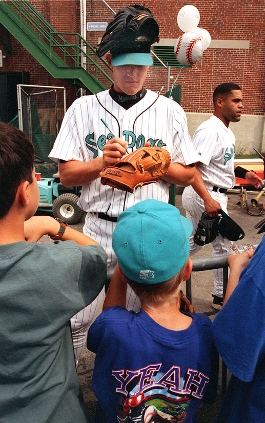 STAFF PHOTO BY DAVID MACDONALD - Monday, September 7, 1998 - Sea Dogs pitcher Mark Richards balances his baseball glove on top of his head while signing sutographs for young fans shortly before the start of the Sea Dogs last game of the season at Hadlock Field.