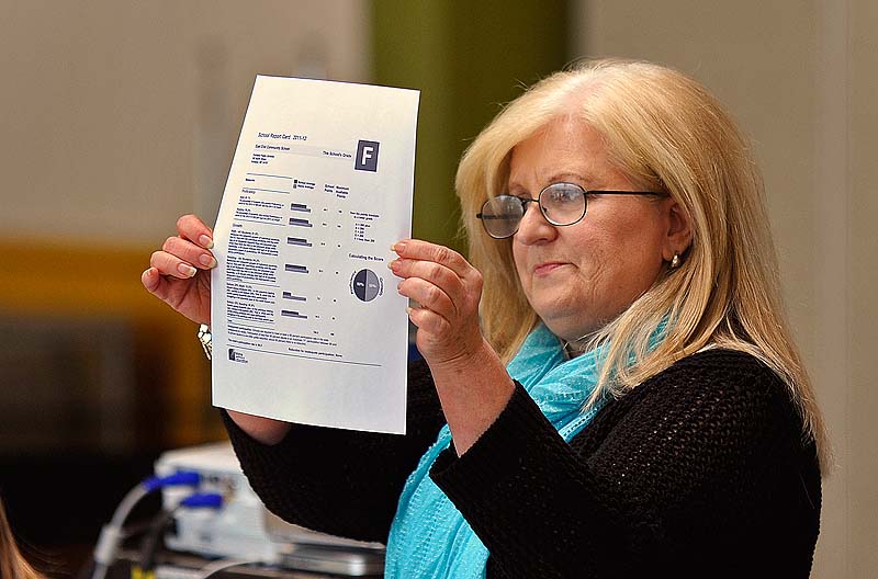 During a meeting with staff, East End Community School Principal Marcia Gendron holds up the report card indicating a letter grade of F that the school received Wednesday after the LePage administration released its new education grading system.
