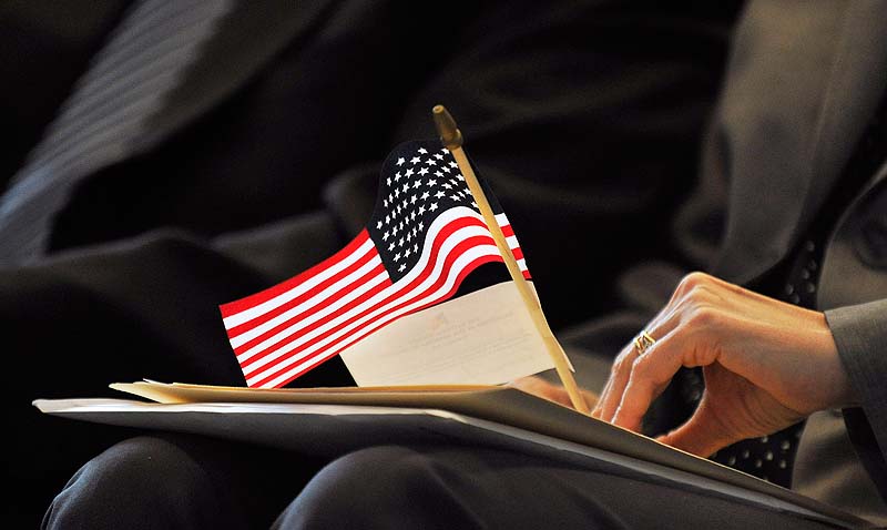 A new citizen holds a small American flag during a naturalization ceremony at Portland High School on Friday.