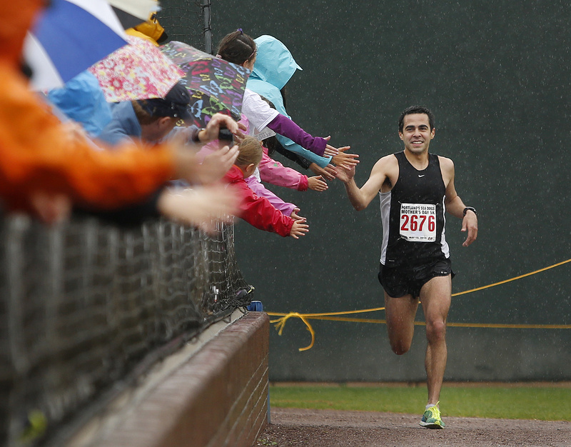 Louie Luchini is all smiles as he rounds the corner toward home plate and the finish line, finishing first in the Portland Sea Dogs Annual Mother's Day 5K road race Sunday.
