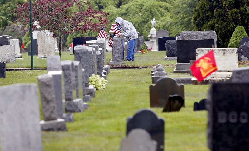 Ron DuPont of South Portland places an American flag at a veteran's grave site Saturday at the Mount Pleasant Cemetery in South Portland. This was the eighth year DuPont has joined veterans and volunteers with South Portland VFW Post 832 to place flags at four South Portland cemeteries. DuPont, who was in college during the Vietnam War, says he volunteers because it is a meaningful way to acknowledge the veterans.