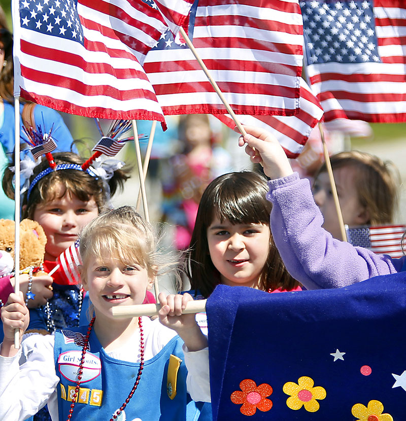 Members of Girl Scout Troop 1845 wave their American flags as they walk in the Scarborough Memorial Day parade and ceremony Monday morning.