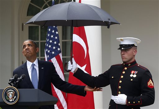 President Barack Obama looks to see if it is still raining as a Marine holds an umbrella for him during his joint news conference with Turkish Prime Minister Recep Tayyip Erdogan, not pictured, on Thursday at the White House.