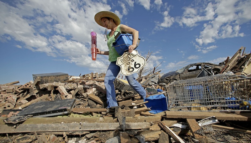 Susan Kates salvages items from a friend's tornado-ravaged home Wednesday, May 22, 2013, in Moore, Okla. Cleanup continues two days after a huge tornado roared through the Oklahoma City suburb, flattening a wide swath of homes and businesses. (AP Photo/Charlie Riedel)