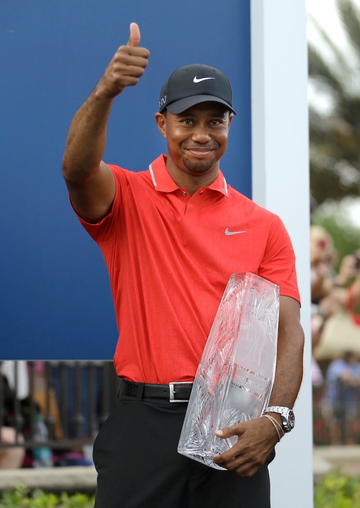 Tiger Woods gives a thumbs-up as he holds the trophy after winning The Players Championship golf tournament Sunday.