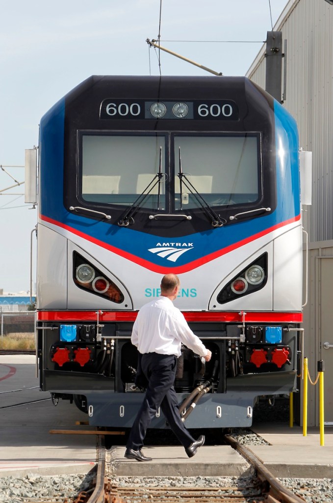 In this photo taken Saturday, May 11, 2013, Michael Cahill, president of Siemens Rail Systems, walks past one of the new Amtrak Cities Sprinter Locomotive that was built by Siemens in Sacramento, Calif. The new electric locomotive will run on the Northeast intercity rail lines and replace Amtrak locomotives that have been in service for 20 to 30 years.(AP Photo/Rich Pedroncelli)