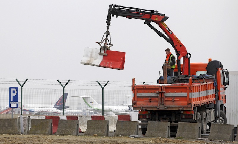 In this Feb. 19, 2013 file photo workers place concrete blocks to block access to a security fence next to the tarmac at Brussels international airport. Police carried out a series of raids on Wednesday, May 8, 2013, in Belgium and detained 31 people in three countries in connection with a spectacular $50 million diamond heist pulled off with apparent clockwork precision at Brussels Airport, a Belgian prosecutor said Wednesday. (AP Photo/Yves Logghe, file)