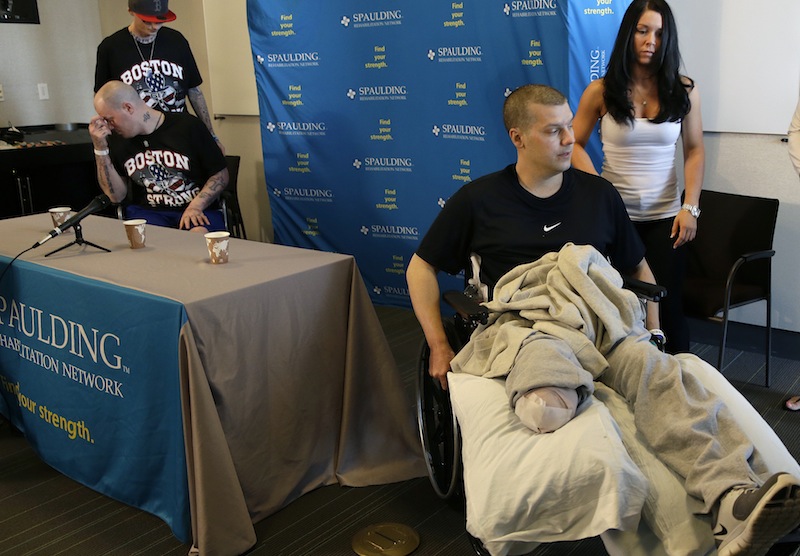 Paul Norden, left, and his brother J.P., right, both suffering limb-loss and major blast related injuries in the Boston Marathon bombing, prepare for a news conference at Spaulding Rehabilitation Hospital in Boston's Charlestown section Monday, May 13, 2013. Helping Paul at left is their younger brother, Jonathan, and at right is JP's girlfriend, Kelly Castine. (AP Photo/Elise Amendola)