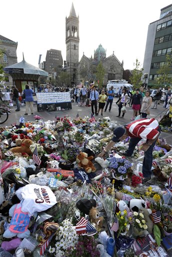 Volunteer Kevin Brown, of Boston, right, places a Teddy bear at a makeshift memorial near the Boston Marathon finish line in Boston's Copley Square on Tuesday in remembrance of the marathon bombing victims.