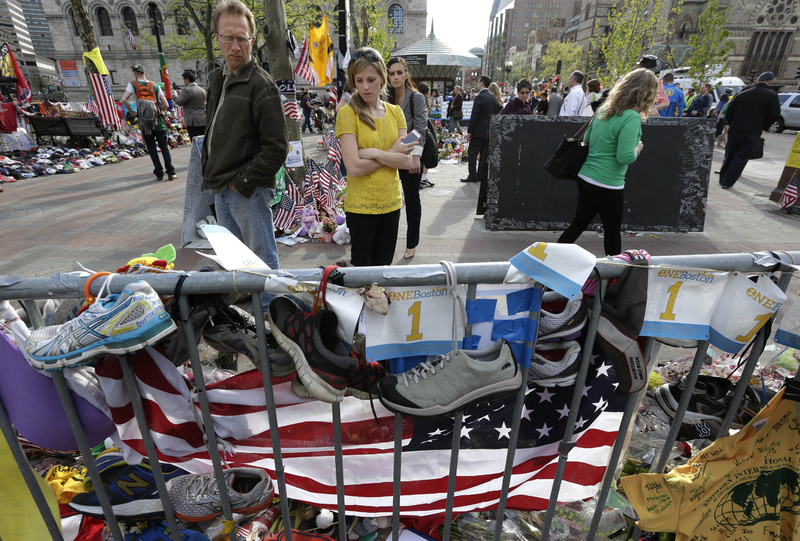 People pause Tuesday to look at a makeshift memorial for those killed and injured in the Boston Marathon bombings near the finish line in Boston's Copley Square.