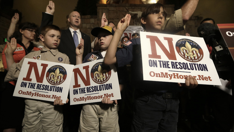Boy Scouts from right, Joey Kalich, 10, Steven Grime, 7, and Jonathon Grime, 9, raise their hands at the close of a news conference held by people against the change in the Boy Scouts of America policy on gay scouts Wednesday in Grapevine, Texas.