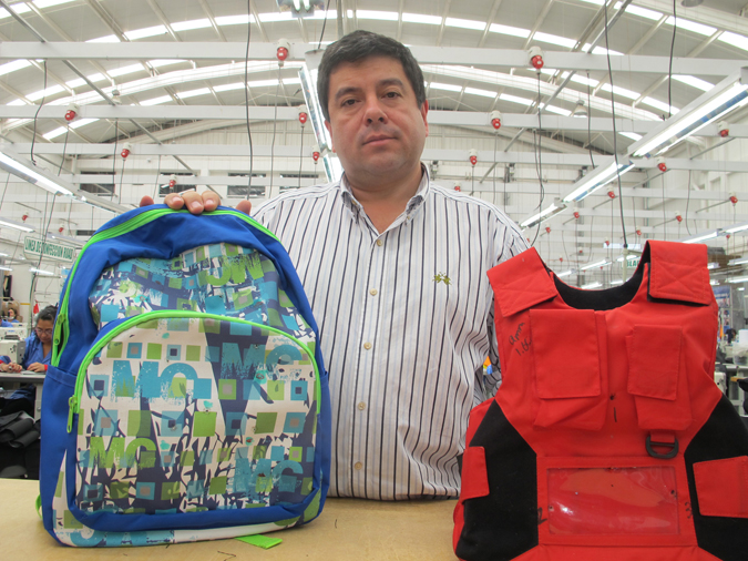 Clothing maker Miguel Caballero, know as "the Armani of bulletprooft clothing," is shown at his factory in Bogota, Colombia, recently. He is holding two of his company's new products for American school children, a bulletproof backpack and vest.