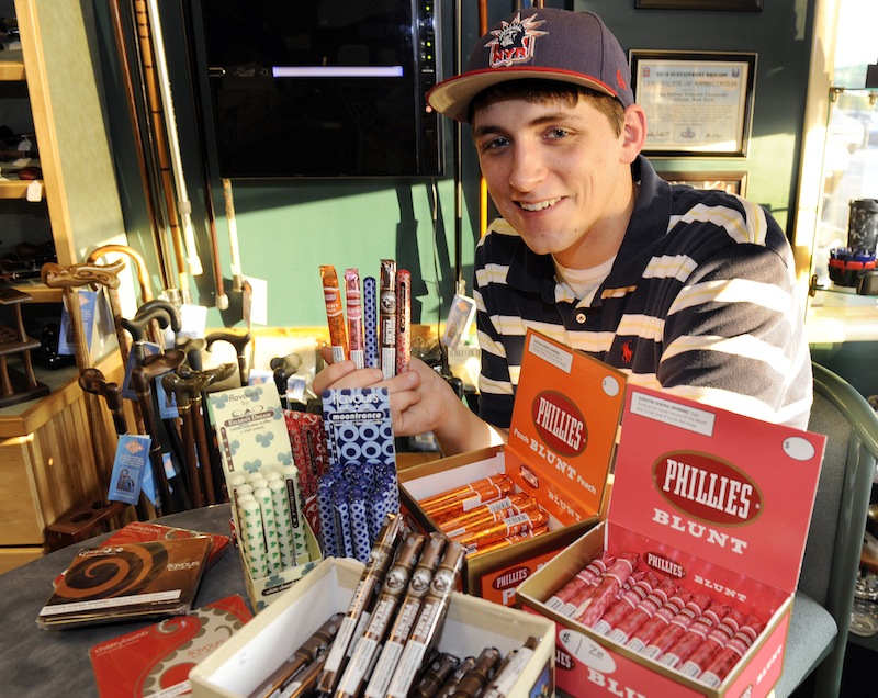 Cigar enthusiast Brendan Glennon poses with a display of candy-flavored cigars at a custom tobacco shop in Albany, N.Y., Friday, May 31, 2013. The American Cancer Society is pushing to make New York the first state to enact a comprehensive restriction on the sale of candy-and fruit-flavored cigarillos, chewing tobacco and tobacco used in water pipes. (AP Photo/Hans Pennink)