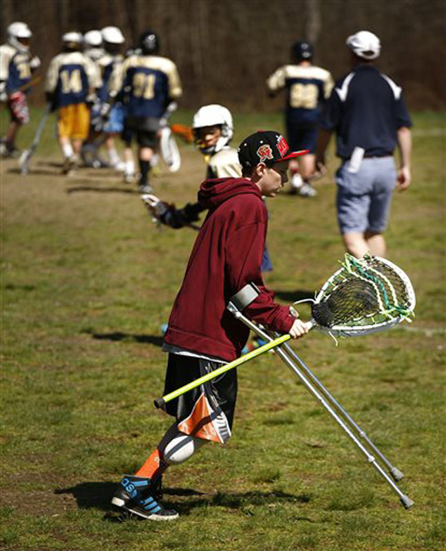Matthew Freitas, 12, of Weymouth, Mass., makes his way across the lacrosse field where his school team is playing. He is helping to coach the team until he can play again.