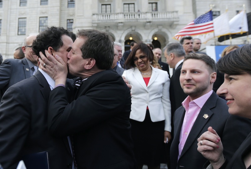 Rhode Island House Speaker Gordon Fox, left, is kissed by R.I. Rep. Frank Ferri, D-Warwick, after a gay marriage bill was signed into law outside the State House in Providence, R.I., Thursday, May 2, 2013. (AP Photo/Charles Krupa)