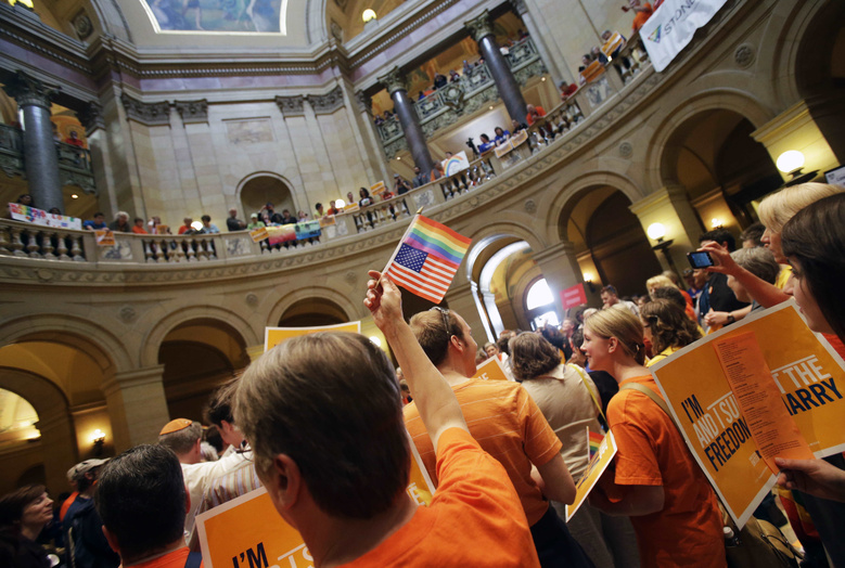 A gay marriage supporter waves the U.S. flag and a rainbow flag as supporters and opponents of Minnesota's gay marriage bill gather in the State Capitol rotunda in St. Paul on Monday in St. Paul, Minn.