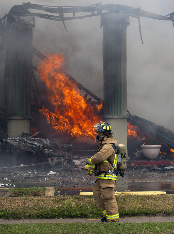 A firefighter stands near flames at the Southwest Inn on Friday in Houston.