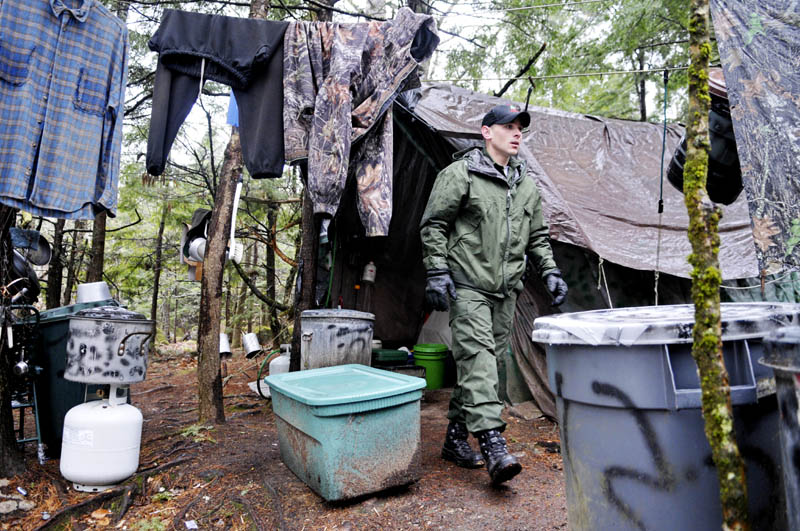 District Game Warden Aaron Cross exits Christopher Knight's camp Tuesday April 9, 2013 in a remote, wooded section of Rome after police inspected the site where Knight is believed to have lived since the 1990s. Police say Knight, who disappeared into the woods near Belgrade in 1986, was a hermit who committed hundreds of burglaries to sustain himself.