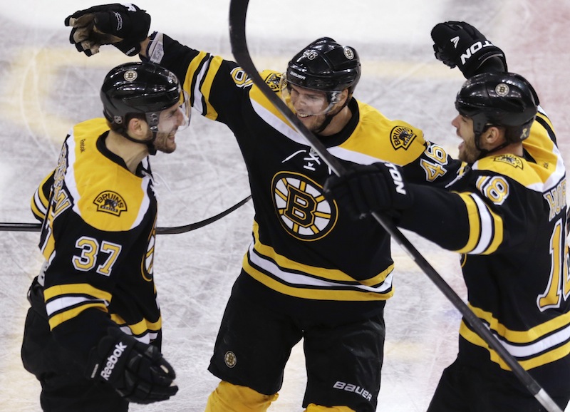 Boston Bruins center Patrice Bergeron, left, is congratulated by teammates David Krejci, center, and Nathan Horton, right, after his goal in the final minute of the third period, which tied the game 4-4 forcing overtime against the Toronto Maple Leafs, in Game 7 of their NHL hockey Stanley Cup playoff series in Boston, Monday, May 13, 2013. (AP Photo/Charles Krupa)