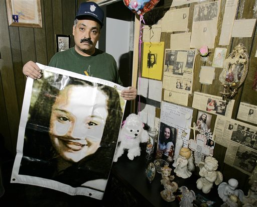 This 2004 file photos shows Felix DeJesus holding a banner showing his daughter's photograph. Gina DeJesus, Amanda Berry and Michele Knight were found Monday in a home near Cleveland.