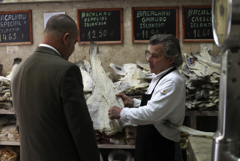 Jose Martins, right, shows a piece of dried cod to a customer in the food store where he works in downtown Lisbon on Thursday.