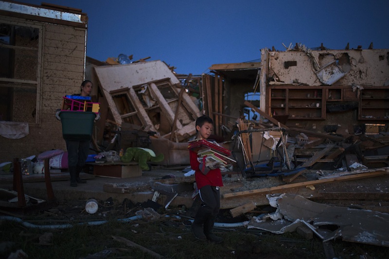 Ethan, 7, carries books he recovered from his damaged house in Moore, Oklahoma, two days after the Oklahoma City suburb was left devastated by a tornado on May 22, 2013. Tornado survivors thanked God, sturdy closets and luck in explaining how they lived through the colossal twister that devastated an Oklahoma town and killed 24 people, an astonishingly low toll given the extent of destruction. (REUTERS/Adrees Latif) :rel:d:bm:GF2E95N05Z501