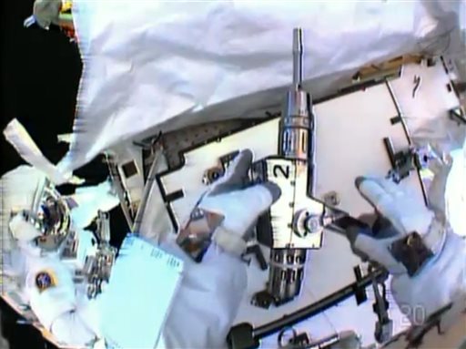 In this image made from video provided by NASA, astronaut Christopher Cassidy, foreground, holds a power wrench as he stows away a suspect coolant pump on the International Space Station on Saturday. Thomas Marshburn is at left. The two astronauts made the spacewalk to replace the pump after flakes of frozen ammonia coolant were spotted outside the station on Thursday.