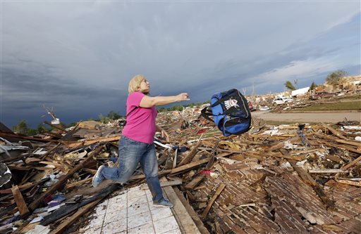 Penny Phillips throws out a bag of salvaged clothing as she goes through the remains of her home on Tuesday in Moore, Okla.