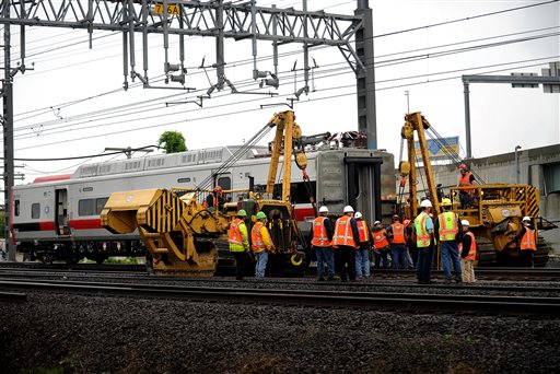 A derailed Metro-North rail car is hoisted back on to the tracks in Bridgeport. Conn. on Sunday. Crews will spend days rebuilding 2,000 feet of track, overhead wires and signals following the collision between two trains Friday evening that injured 72 people,